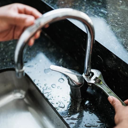Instalador ajustando un grifo de cocina con una llave