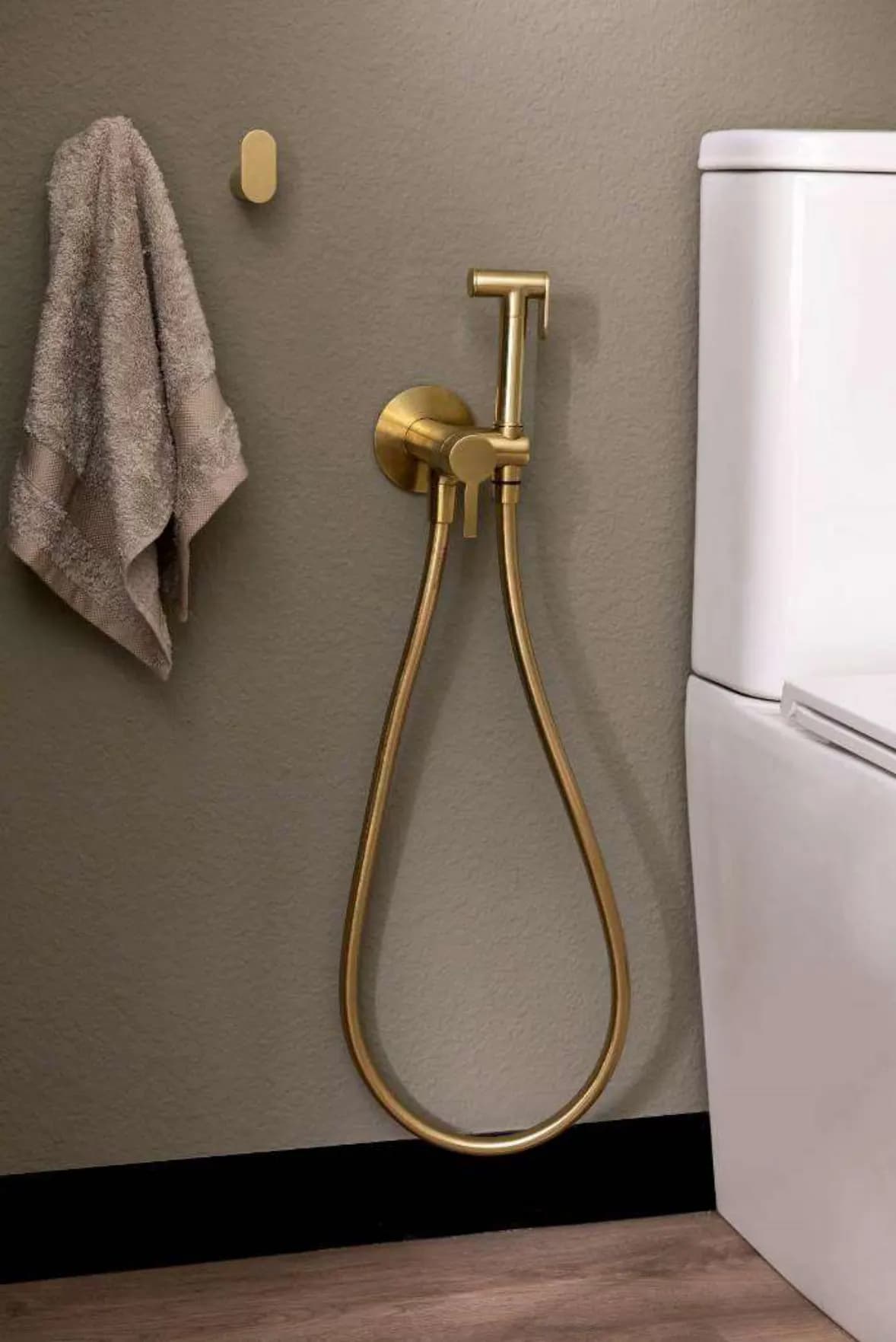 Handbrause als Bidet-Ersatz: WC Magnet, Oberfläche gebürstetes Gold, von Ramon Soler®. Zwei Haken der Kollektion Ergos von Ramon Soler® in gebürstetem Gold.
